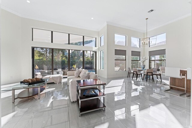 living room with a chandelier, a high ceiling, a wealth of natural light, and crown molding