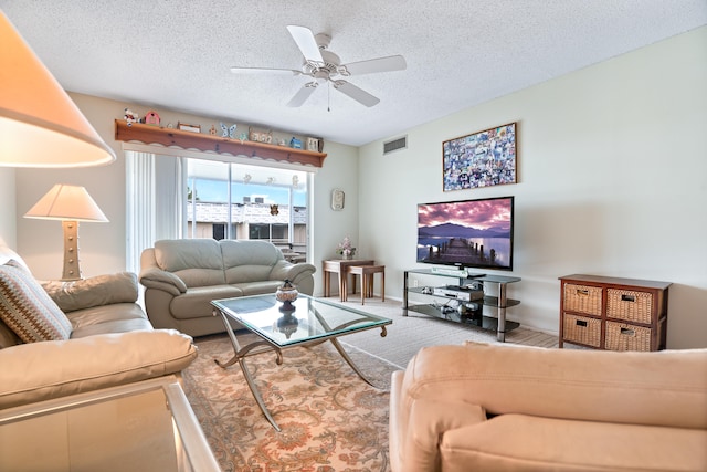 carpeted living room with ceiling fan and a textured ceiling