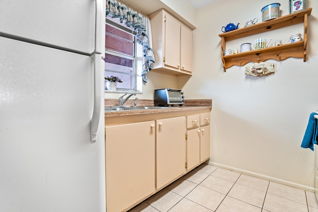 kitchen featuring white fridge, light tile patterned floors, and sink