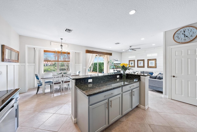 kitchen featuring dark stone counters, decorative light fixtures, gray cabinets, and light tile patterned floors