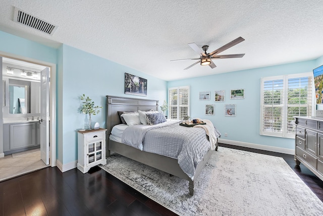 bedroom featuring dark wood-type flooring, connected bathroom, and a textured ceiling