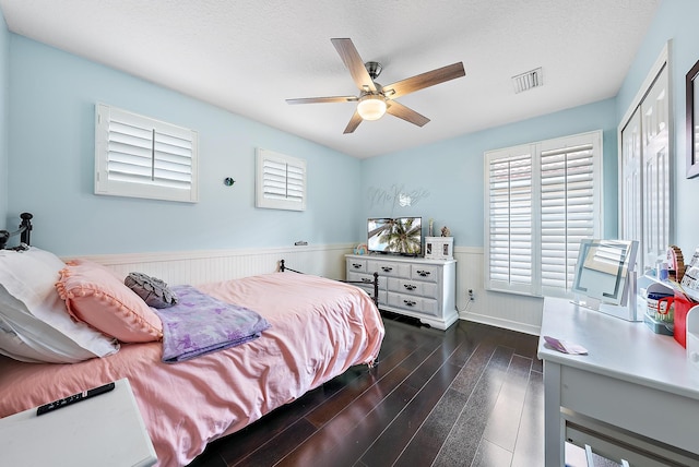 bedroom with dark hardwood / wood-style flooring, ceiling fan, a closet, and a textured ceiling