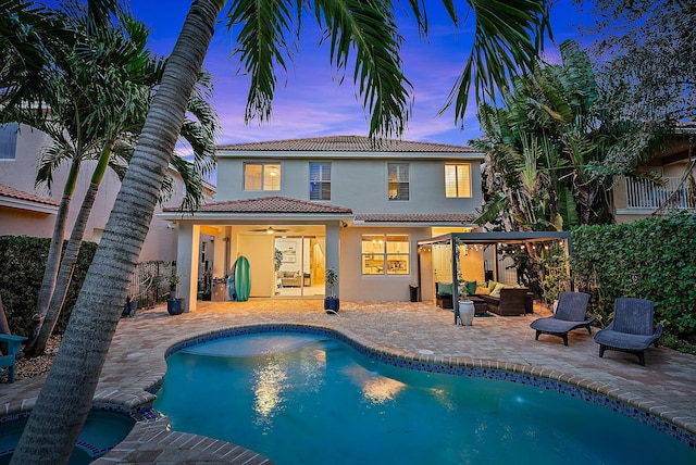 back house at dusk featuring a patio area, outdoor lounge area, and ceiling fan