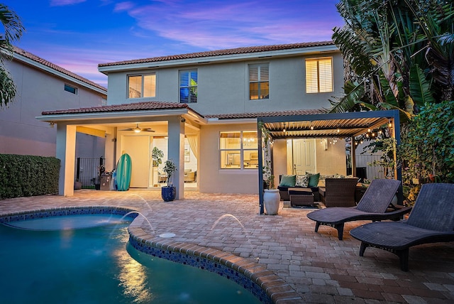 back house at dusk featuring pool water feature, ceiling fan, an outdoor living space, and a patio area