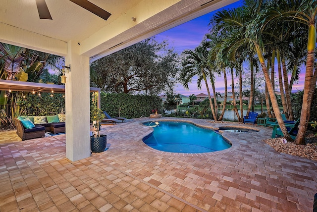 pool at dusk with an in ground hot tub, outdoor lounge area, and a patio