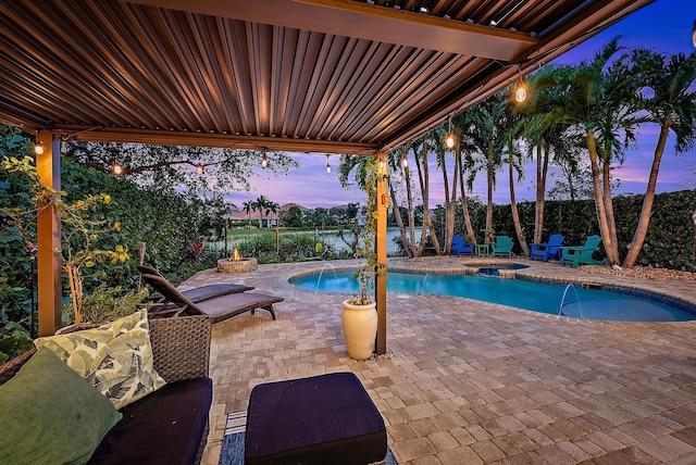 pool at dusk featuring an in ground hot tub, pool water feature, and a patio