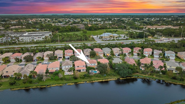 aerial view at dusk featuring a water view