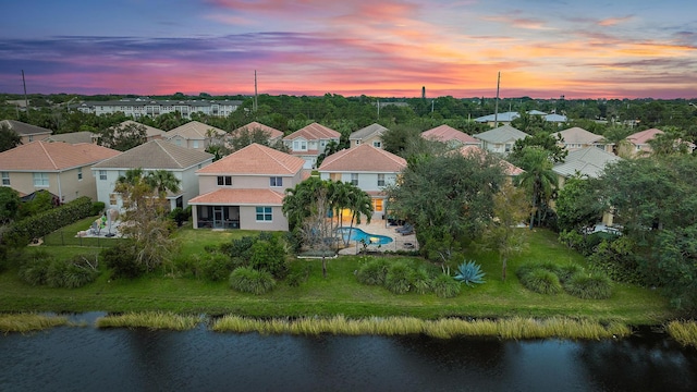 aerial view at dusk featuring a water view