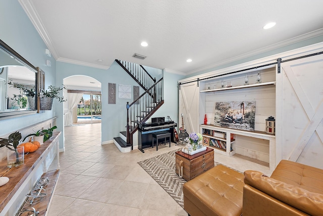 living room with light tile patterned flooring, ornamental molding, and a barn door