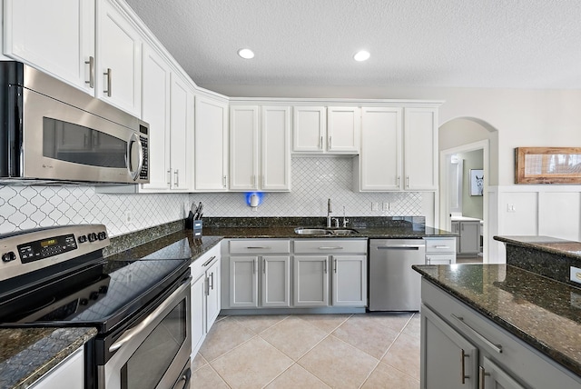 kitchen featuring sink, appliances with stainless steel finishes, white cabinetry, gray cabinetry, and dark stone countertops