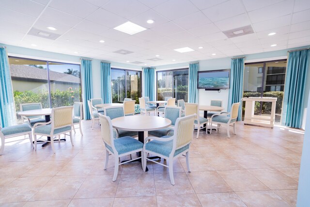 tiled dining room featuring a paneled ceiling and a healthy amount of sunlight