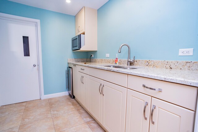 kitchen featuring light stone countertops, sink, and light tile patterned floors