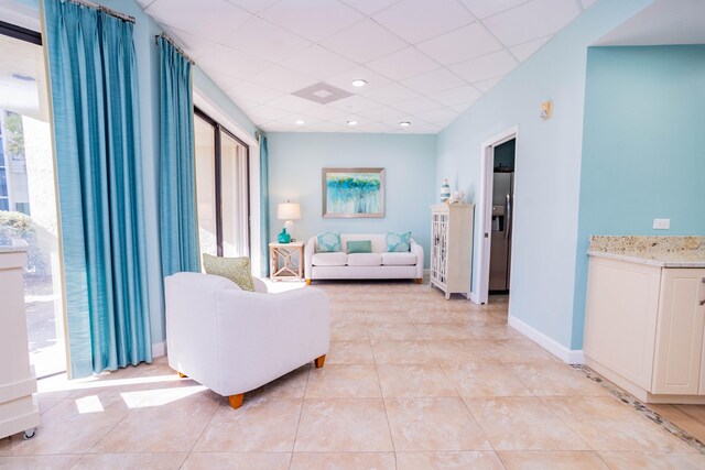 tiled living room with a paneled ceiling