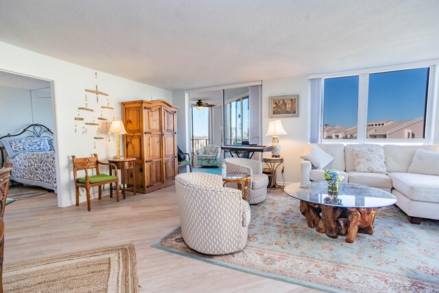 living room featuring a textured ceiling, light hardwood / wood-style flooring, and ceiling fan