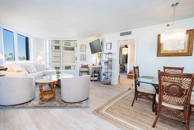 living room featuring ceiling fan with notable chandelier and light hardwood / wood-style floors