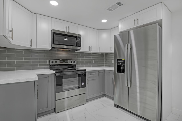 kitchen with white cabinets, backsplash, stainless steel appliances, and gray cabinetry