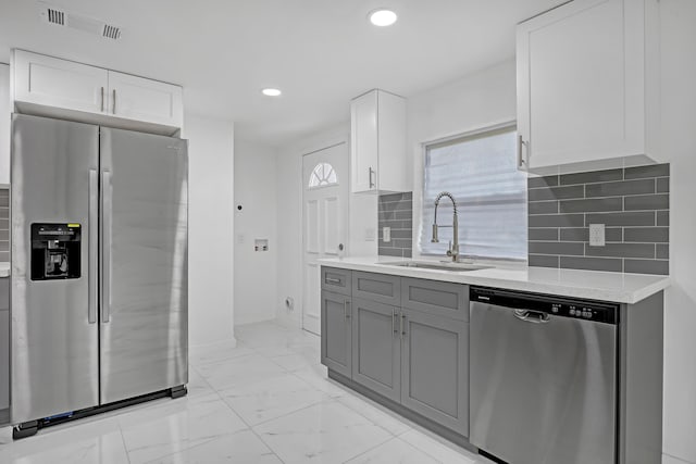 kitchen with backsplash, gray cabinetry, stainless steel appliances, sink, and white cabinetry