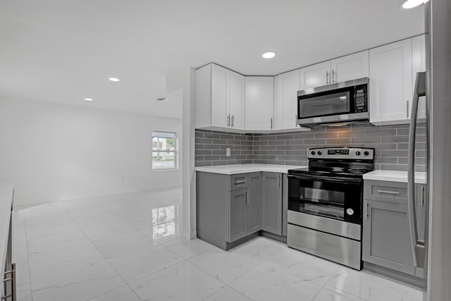 kitchen featuring gray cabinets, stainless steel appliances, and tasteful backsplash