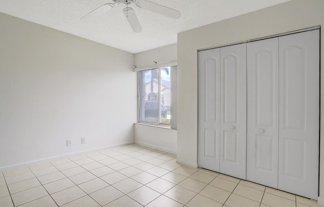 unfurnished bedroom featuring ceiling fan, light tile patterned floors, a closet, and a textured ceiling