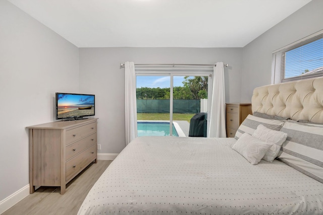 bedroom with access to outside, multiple windows, and light wood-type flooring