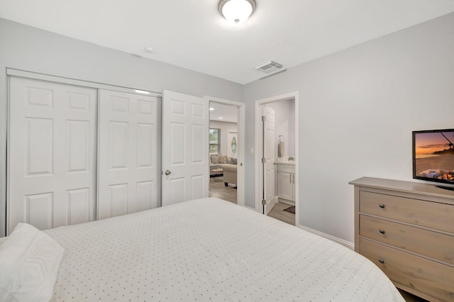 bedroom featuring light hardwood / wood-style flooring, ensuite bath, and a closet