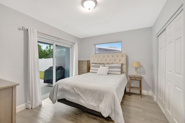 bedroom with access to exterior, light wood-type flooring, a closet, and multiple windows