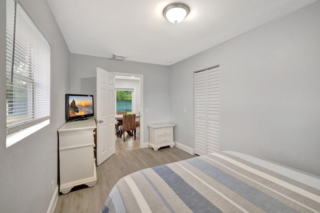 bedroom featuring a closet, light hardwood / wood-style floors, and multiple windows