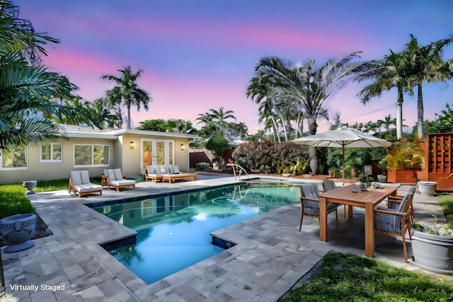 pool at dusk featuring an outdoor hangout area, french doors, and a patio