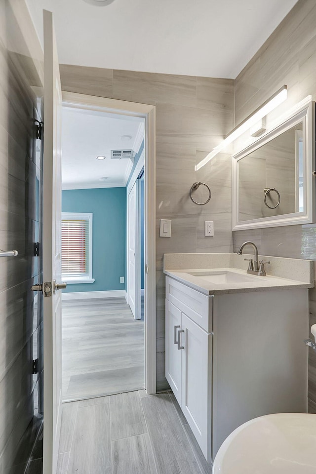 bathroom with toilet, vanity, tile walls, and crown molding