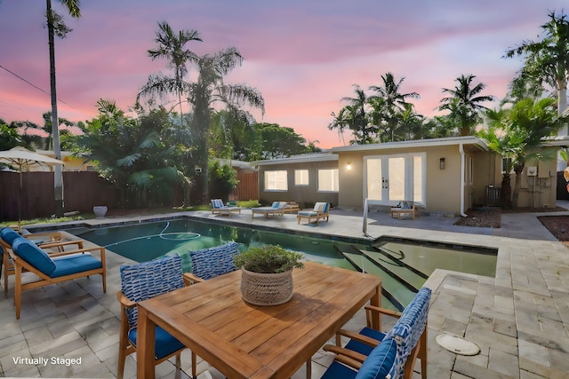 pool at dusk featuring a patio area and french doors