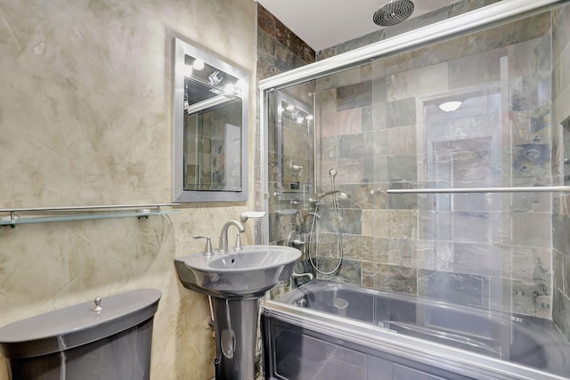 bathroom featuring toilet and bath / shower combo with glass door