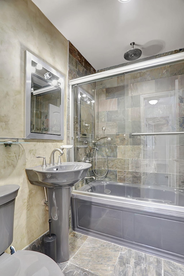 bathroom featuring combined bath / shower with glass door and toilet