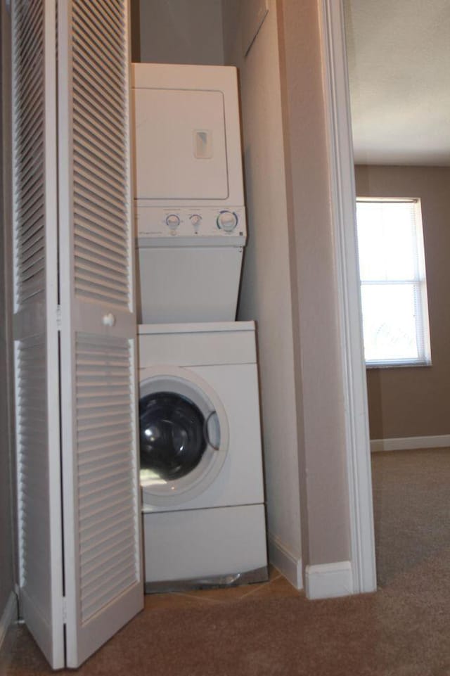 laundry area with carpet flooring and stacked washer / dryer