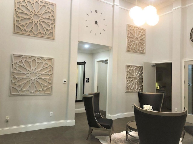 interior space with dark tile patterned floors, ornamental molding, a high ceiling, and a chandelier