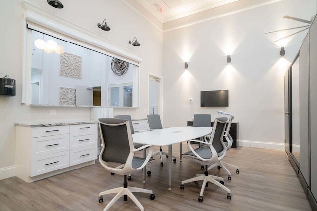 office with crown molding, a high ceiling, and light wood-type flooring