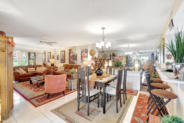 dining area with a textured ceiling, light tile patterned flooring, and ceiling fan with notable chandelier