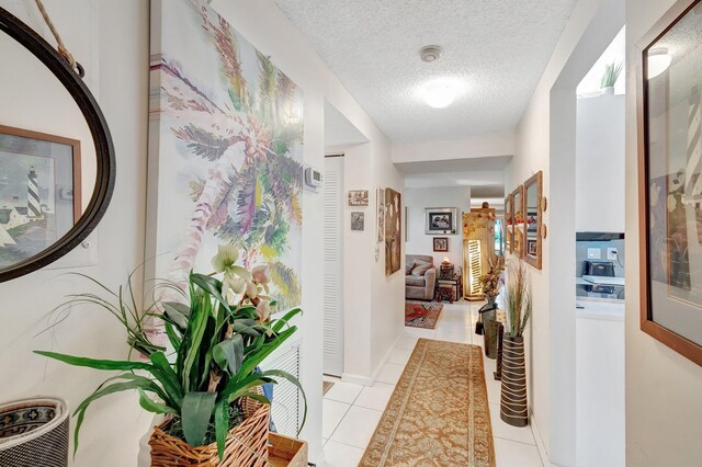 living room with ceiling fan, light tile patterned floors, and a textured ceiling