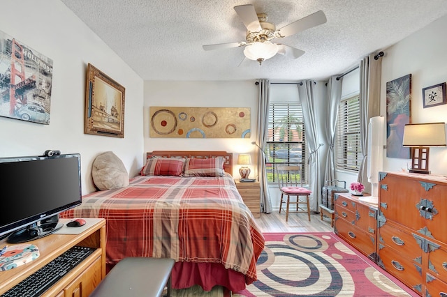 bedroom with ceiling fan, light hardwood / wood-style floors, and a textured ceiling