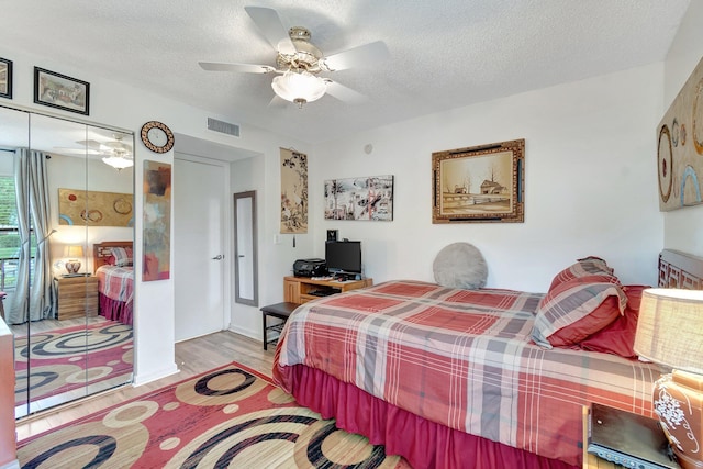 bedroom featuring a textured ceiling, light hardwood / wood-style flooring, and ceiling fan