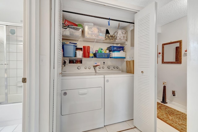 laundry room with washer and clothes dryer, light tile patterned floors, and a textured ceiling