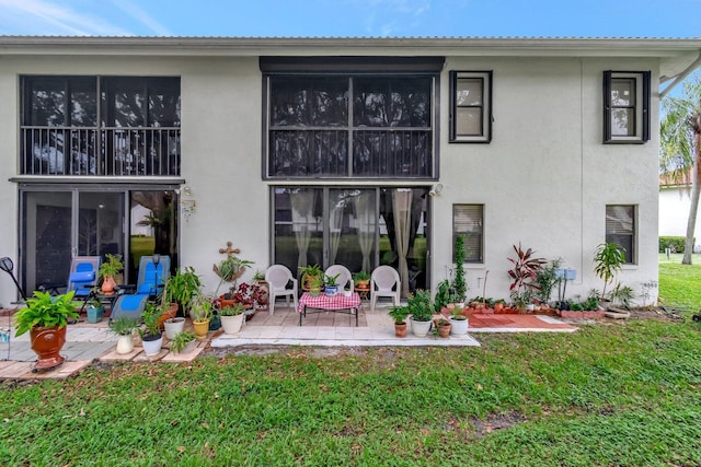 9668 Sills Dr Unit 101, Boynton Beach, FL 33437 - rear view of property featuring stucco siding, a patio area, and a lawn