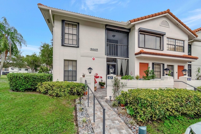 9668 Sills Dr Unit 101, Boynton Beach, FL 33437 - view of front of property with stucco siding, a tiled roof, and a front lawn
