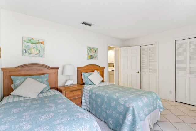 bedroom featuring light tile patterned floors and multiple closets