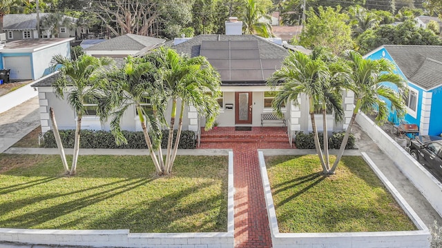 view of front facade with a residential view, roof mounted solar panels, roof with shingles, and a front lawn