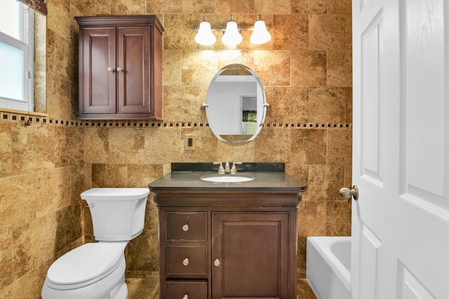 bathroom with a bathing tub, vanity, tile walls, and toilet