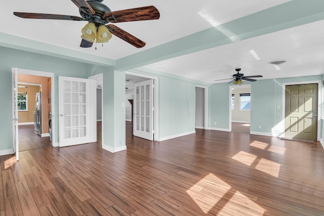 unfurnished living room with french doors, ceiling fan, and dark wood-type flooring