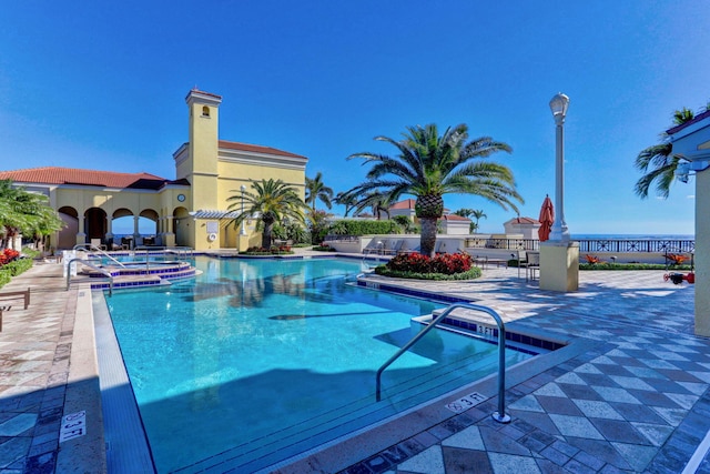 view of swimming pool featuring a hot tub and a patio area