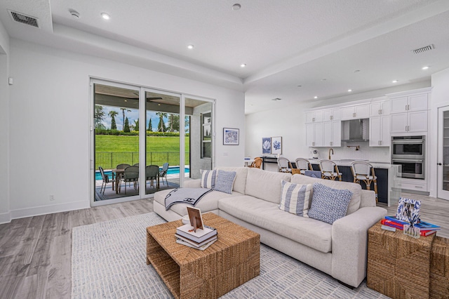 living room featuring a tray ceiling and light hardwood / wood-style flooring