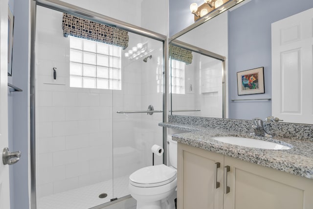 full bath featuring toilet, a stall shower, and vanity