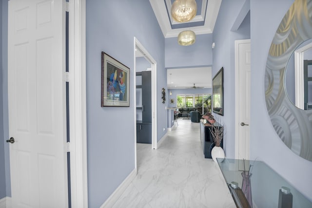 corridor with marble finish floor, crown molding, baseboards, and an inviting chandelier